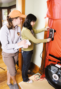 photograph of Emily Weissinger and Yin Liang measuring a home’s ventilation